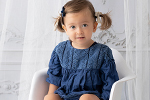 Mädchen im blauem Kleid auf dem Schaukelstuhl
